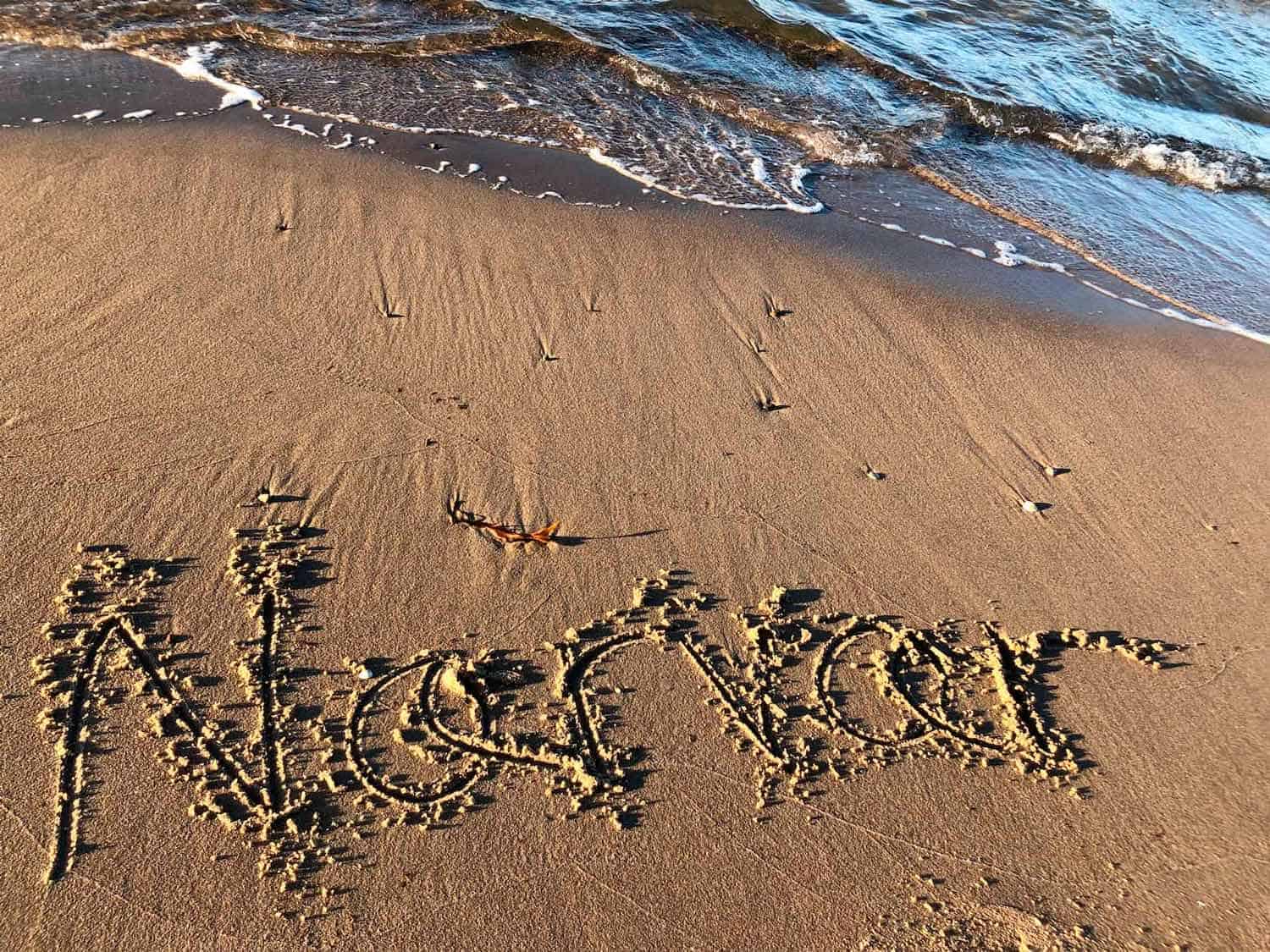 Nærvær skrevet i sandet på en strand - Nærvær